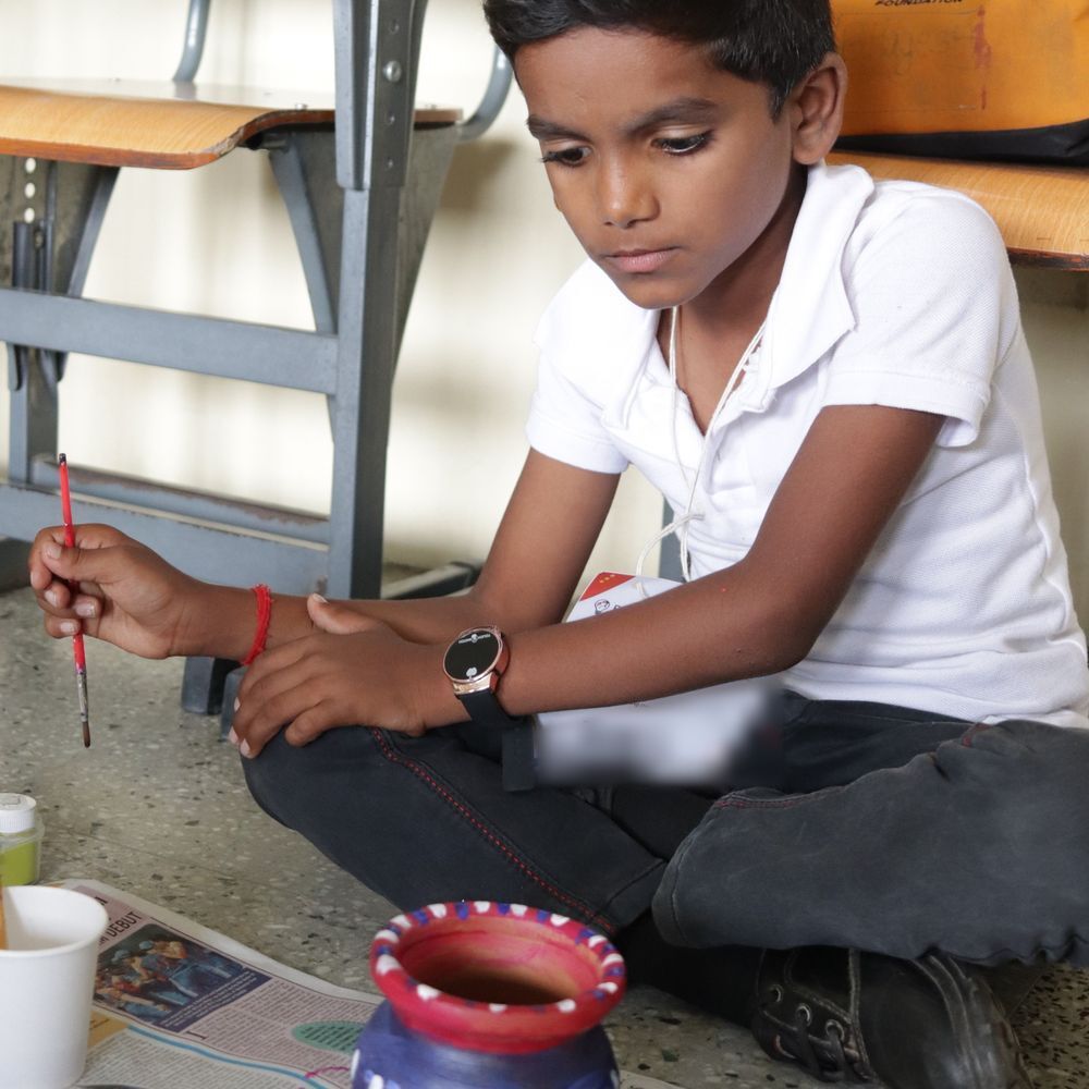 A boy painting a clay pot at Kalakriti 3.0